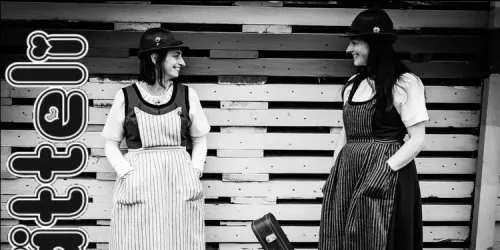 Satteli sisters in traditional Swiss dress, smiling at each other