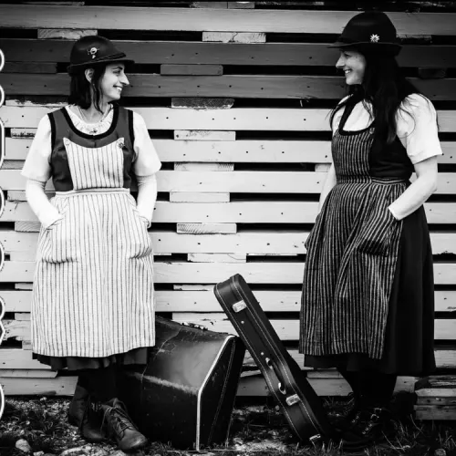 Satteli sisters in traditional Swiss dress, smiling at each other
