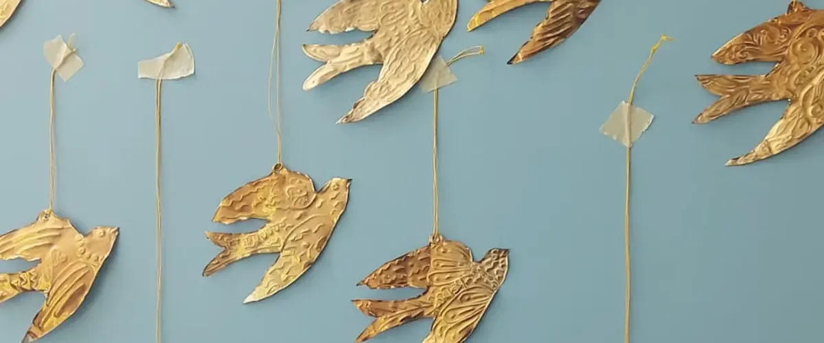 Handmade metallic flock of birds against a blue wall