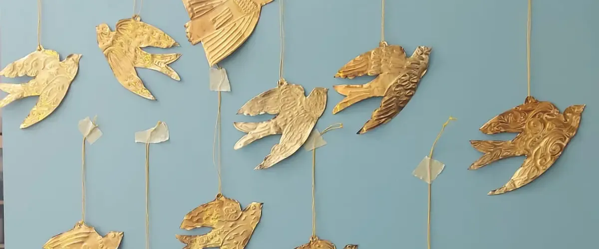 Handmade metallic flock of birds against a blue wall