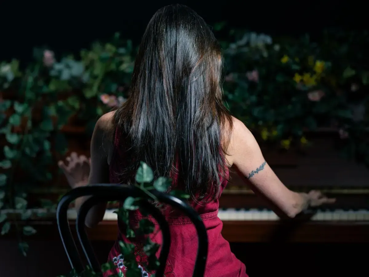 Helen sitting at a piano with ivy spilling over the top