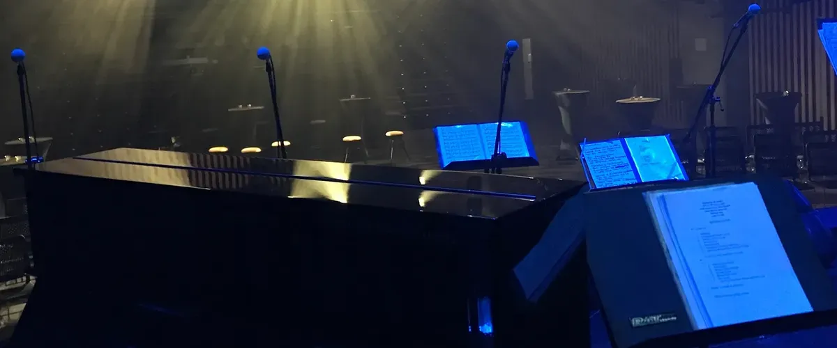Looking out from the stage, with upright Yamaha piano and 4 microphones on the stage